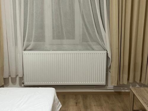 a bedroom with a radiator and a window with curtains at Hotel Tatul in Momchilgrad