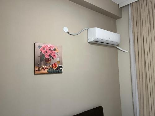 a room with a wall mounted light and a picture of flowers at Hotel Tatul in Momchilgrad