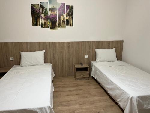 two beds in a room with white sheets at Hotel Tatul in Momchilgrad