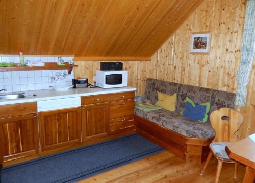 a kitchen with a couch in the corner of a room at Kleines Ferienhaus Koglerhütte in Rossleithen