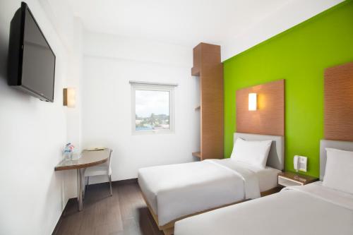 a hotel room with two beds and a green wall at Amaris Hotel Samarinda in Samarinda