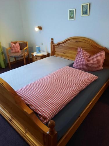 a wooden bed with a red and white checkered blanket at Landgasthof Rotlipp Gästezimmer in Ortenberg