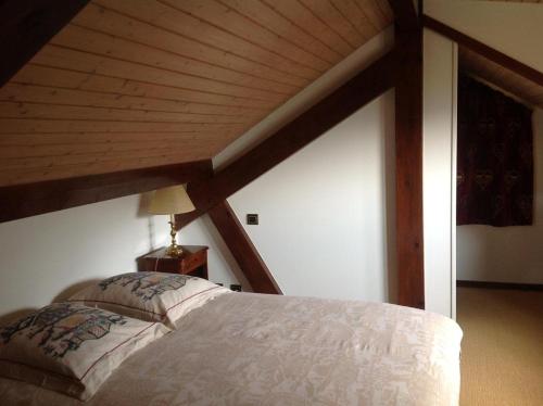 Cama en habitación con techo de madera en Les Grangettes 2 - DUPLEX - WIFI gratuite, en Les Carroz d'Araches