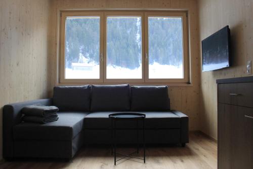a living room with a couch and two windows at Bergreich Appartement 3 in Schoppernau