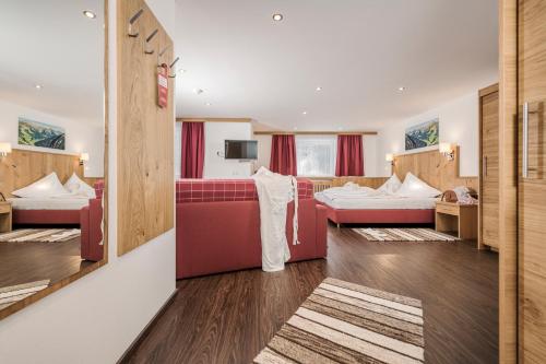 トゥクスにあるHotel Kirchlerhofのベッド2台と赤いソファが備わるホテルルームです。