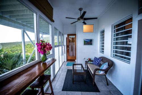 a screened in porch with a couch and flowers at Papaya Suite at Sunset Serenade in Enighed