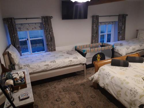 a bedroom with two beds and a couch and two windows at Upper Eyton Farmhouse B&B in Shrewsbury