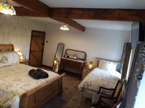 a bedroom with two beds and a desk and a mirror at Upper Eyton Farmhouse B&B in Shrewsbury
