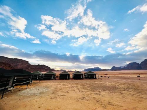 a group of tents in the desert under a cloudy sky at Shakria Bedouin Life Camp in Wadi Rum