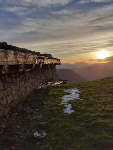 a stone wall on top of a mountain with the sunset at Ferienwohnung mit wundervollen Bergblick in Lenggries