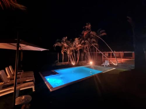 a swimming pool at night with an umbrella and chairs at Bossa Beach House in Ilha do Mel