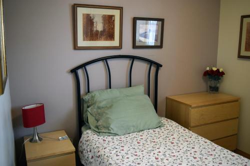 a bedroom with a bed and a red lamp and pictures at The Dewberry Homestay B&B in Edmonton