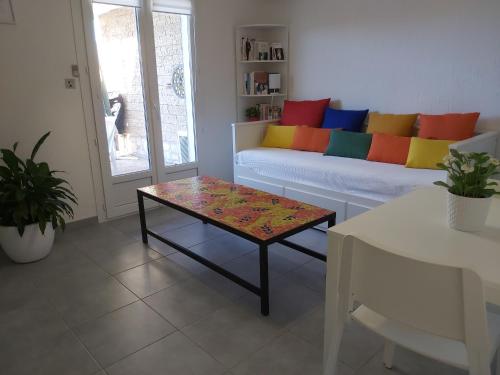 a living room with a couch with colorful pillows at Appartement T2 Six Fours Cap Negre,1 mn à pied de la mer in Six-Fours-les-Plages