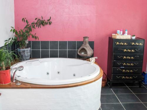 y baño con bañera y pared de color rosa. en Knakkergård, en Snedsted