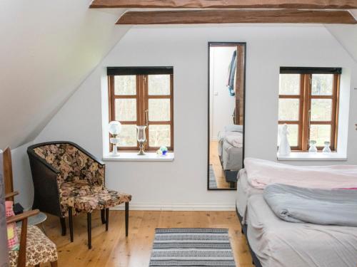 een slaapkamer met een bank en een stoel en 2 ramen bij Knakkergård in Snedsted