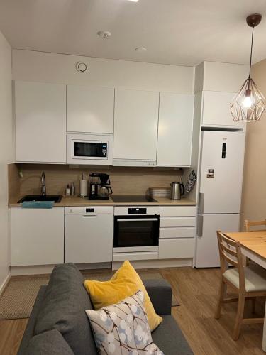 une cuisine avec des placards blancs et un canapé dans le salon dans l'établissement Cozy centre apartament Kuopio, à Kuopio