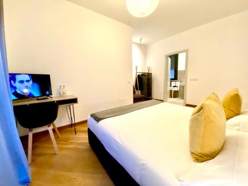 Schlafzimmer mit einem Bett und einem Schreibtisch mit einem TV in der Unterkunft Palazzina B - Smart Rooms in Genua
