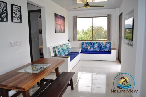 ein Wohnzimmer mit einem Holztisch und blauen Stühlen in der Unterkunft Natural View in Melgar