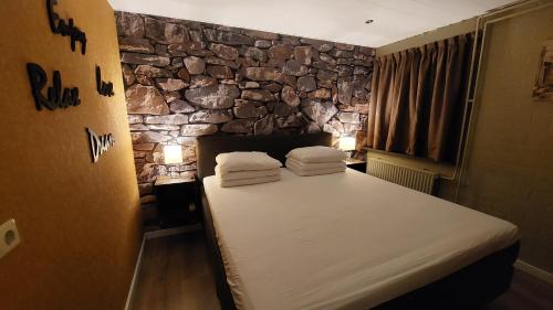een bed in een kamer met een stenen muur bij Vakantiehuis Amber in Simpelveld