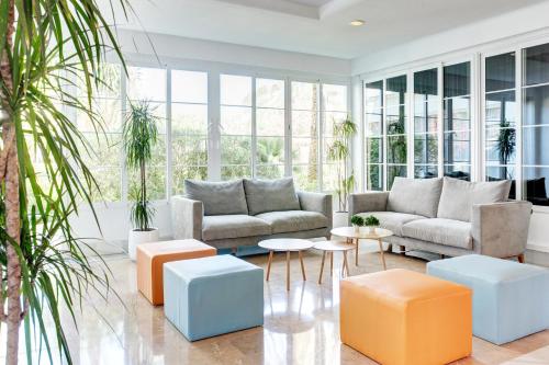 a living room with couches and tables and plants at Grupotel Alcudia Suite in Playa de Muro