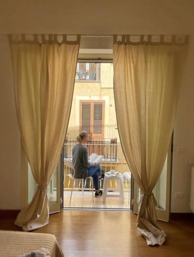 a woman sitting on a chair on a balcony looking out the window at B&B Evelyne in Taormina