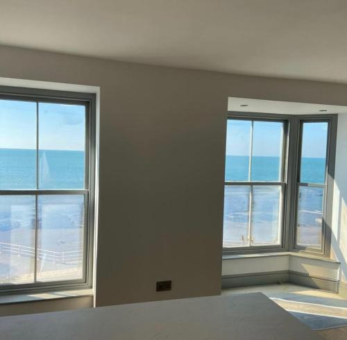an empty room with three windows and the ocean at Sea View Apartment - Sleeps 2 in Aberystwyth