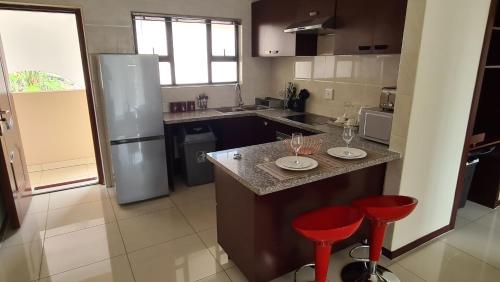a kitchen with a counter and two red stools at LilyPark Lodge in Rustenburg