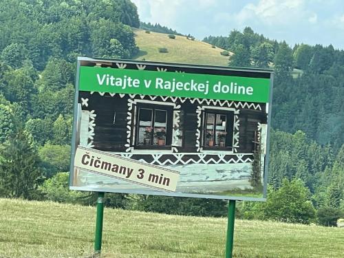 a sign in the middle of a field with a building at Chalupa Čičmany in Čičmany