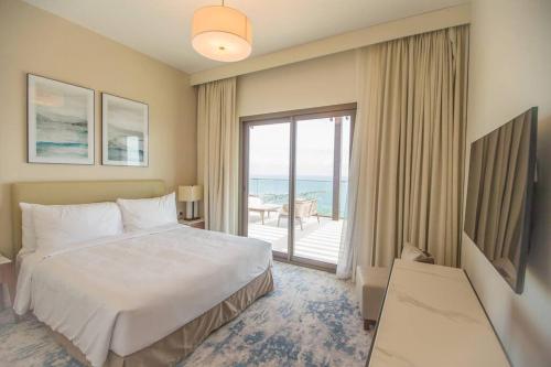 a bedroom with a bed and a balcony with the ocean at Luxurious 5 Bedroom Apartment - Full Ocean view in Al Aqah