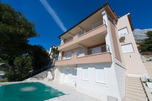 een huis met een zwembad ervoor bij Apartments KARLO in Baška Voda