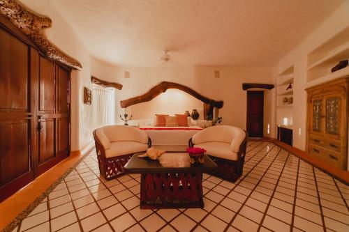 a large bedroom with a bed and two chairs at Espuma Hotel - Adults Only in Zihuatanejo