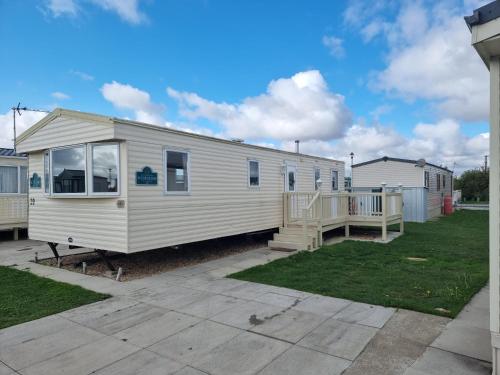 a white mobile home with a porch and a deck at Meadow Lakes 39 in Skegness