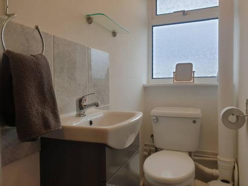a bathroom with a sink and a toilet and a window at Stylish 3 Bedroom House with Free Parking in Norwich