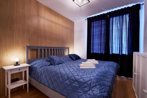 a bedroom with a bed with a blue comforter and a window at RV Apartment Jantár in Starý Smokovec