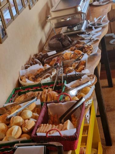 a buffet line with different types of breads and pastries at Recanto dos Moinhos - Boutique Hotel in Campos do Jordão