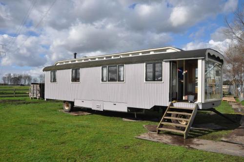 a white trailer parked in a field with a ladder at Gypsy Waggon - A villa on wheels in Amsterdam