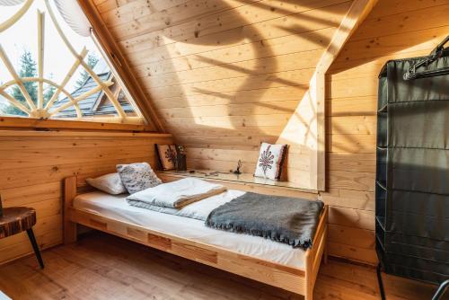 a bed in a log cabin with a window at Litworowy Dom in Kościelisko
