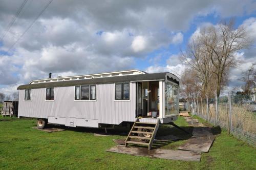 a white trailer parked in a field with a ladder at Gypsy Waggon - A villa on wheels in Amsterdam