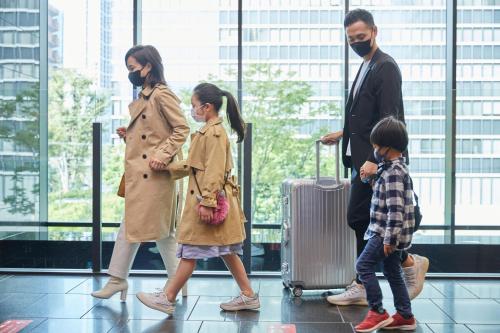 a family walking through a airport with their luggage at karaksa hotel grande Shin-Osaka Tower in Osaka