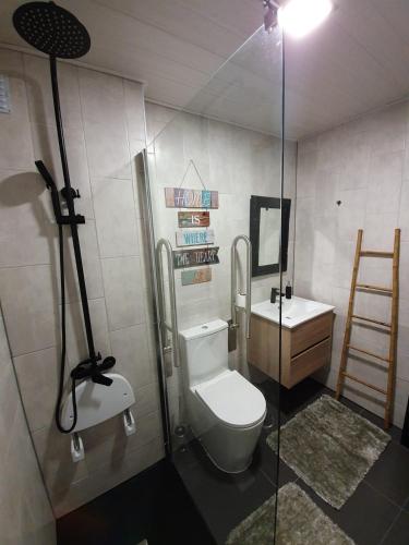 a bathroom with a toilet and a glass shower at Apartment by the Beach Praia da Areia Branca in Lourinhã