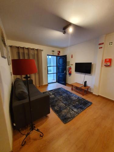 a living room with a couch and a television at Apartment by the Beach Praia da Areia Branca in Lourinhã