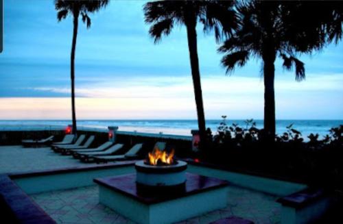 a fire pit on the beach with palm trees and the ocean at Stay ON the beach! Beautiful building and location! in Daytona Beach