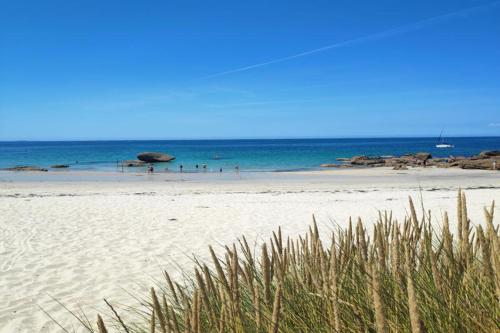 a beach with a group of people in the ocean at Maison à 200m des plages avec jacuzzi in Trégunc