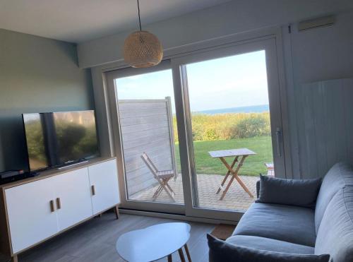 un soggiorno con divano e porta scorrevole in vetro di Superbe appartement restauré avec vue sur mer. a Wimereux