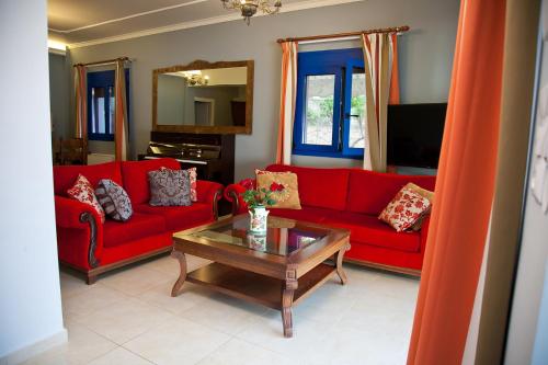 a living room with red couches and a coffee table at Villa Niki in Plataria