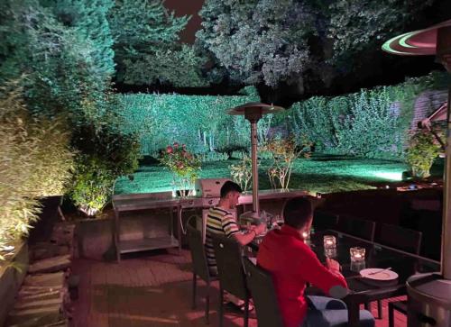 deux hommes assis à une table dans un jardin la nuit dans l'établissement Le jacuzzi de Marie, à Tourcoing