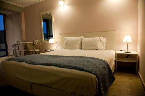 a bedroom with a large white bed with two lamps at Villa Niki in Plataria