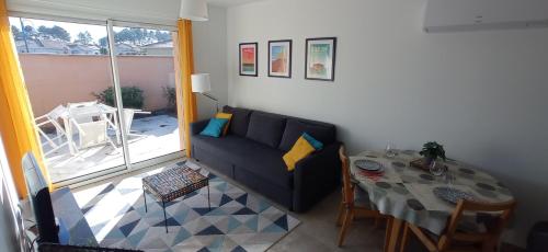een woonkamer met een bank en een tafel bij La Petite Maison du Bassin d'Arcachon - 40 m2, climatisée, indépendante et au calme in Audenge