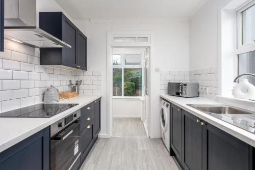 a kitchen with black cabinets and a sink at Wellington View - Donnini Apartments in Ayr