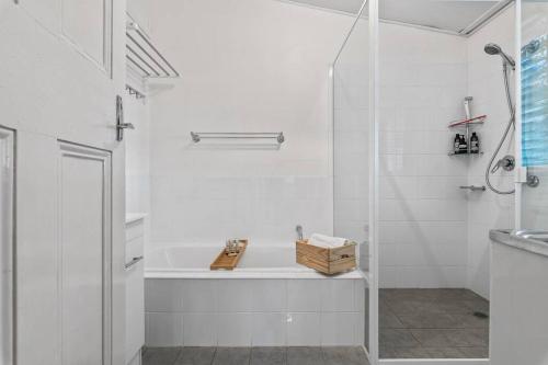 a white bathroom with a tub and a shower at HOLIDAYS ON LOVE STREET / HUNTER VALLEY in Cessnock